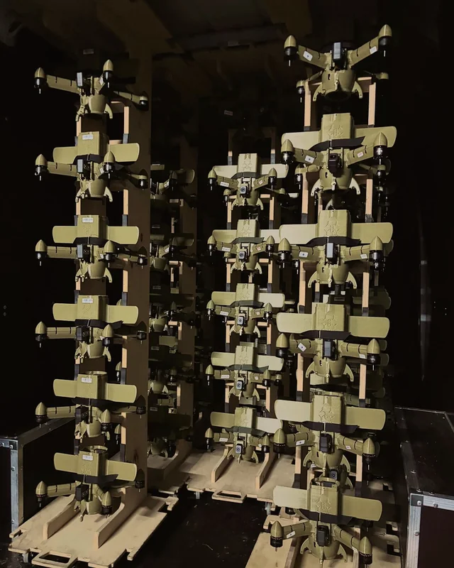 Racks of olive-green FPV strike drones lined up in a workshop.