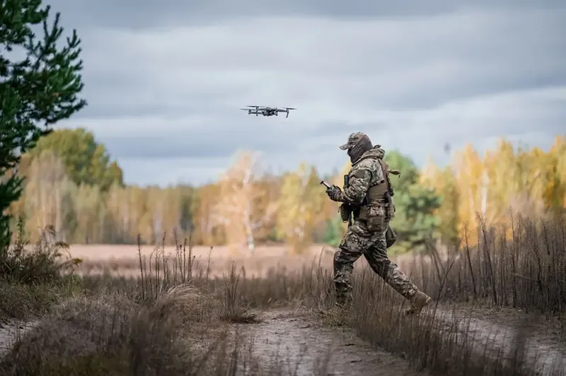 FPV drone hovering low over a misty training range.