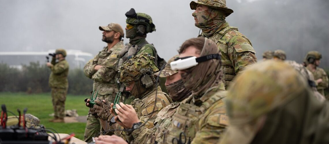 Soldiers in camouflage operating drone controllers in a misty field.
